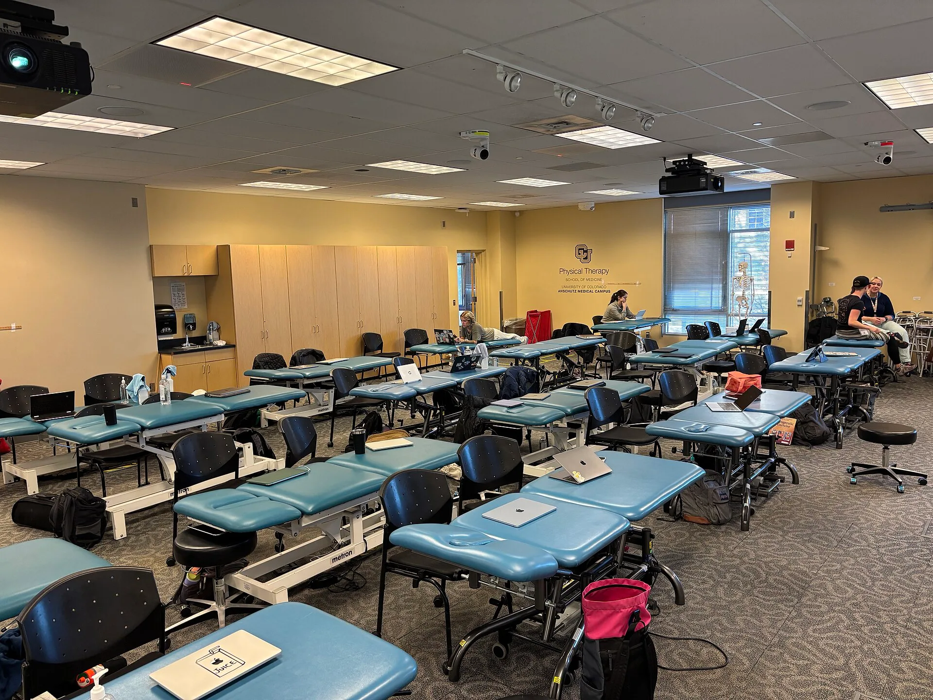 This image shows the Physical Therapy classroom at the University of Colorado Anschutz in 2025. The room contains multiple treatment tables, chairs, anatomical models, laptops, and educational supplies, illustrating a hands-on clinical learning environment for Doctor of Physical Therapy students. Th. Physical Therapy Local SEO Checklist for Clinics