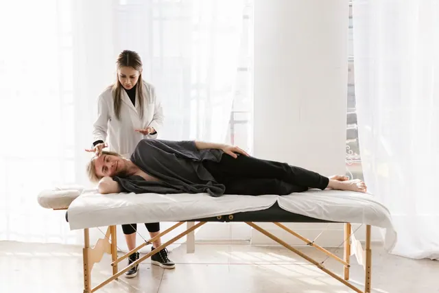 Young woman therapist provides relaxing massage therapy to a male client indoors.